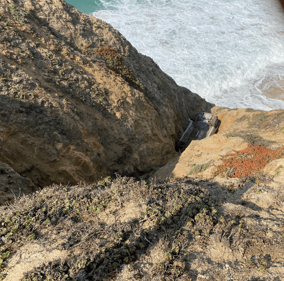 The vehicle sits at the bottom of a cliff at Montara State Beach along Highway 101 in San Mateo County.