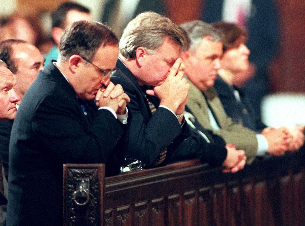 Then-New York Mayor Rudolph Giuliani (L) prays during a memorial service at St. Patrick