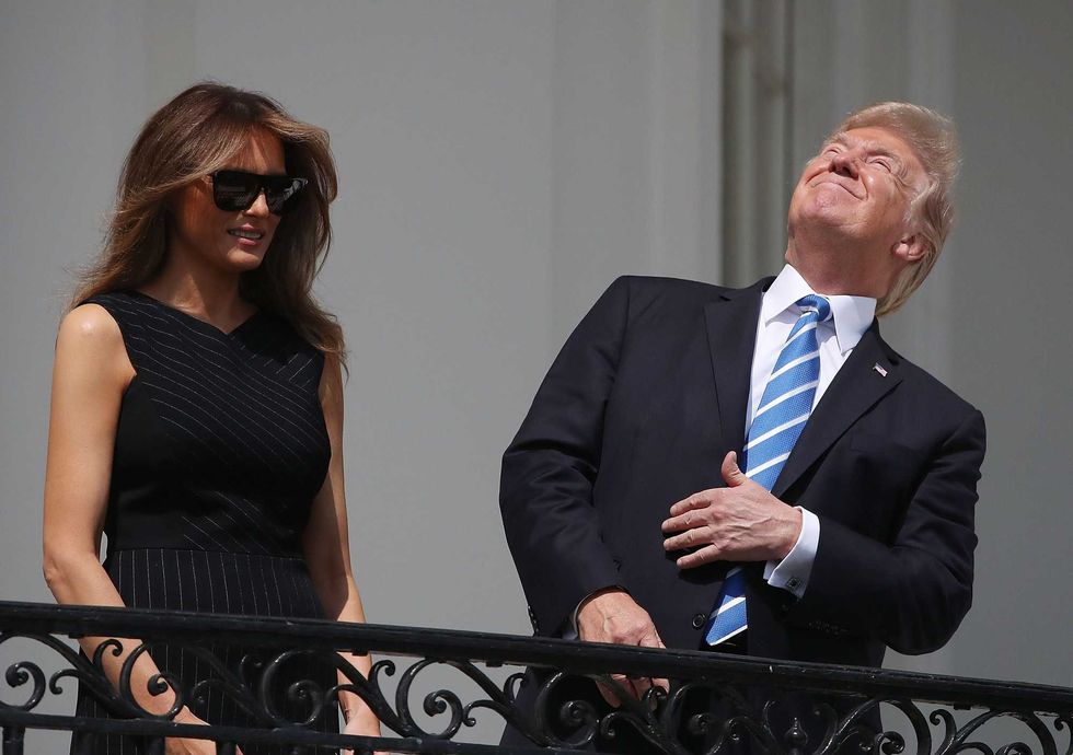 Then-President Donald Trump looks up toward the Solar Eclipse while joined by his wife first lady Melania Trump on the Truman Balcony at the White House on August 21, 2017 in Washington, DC