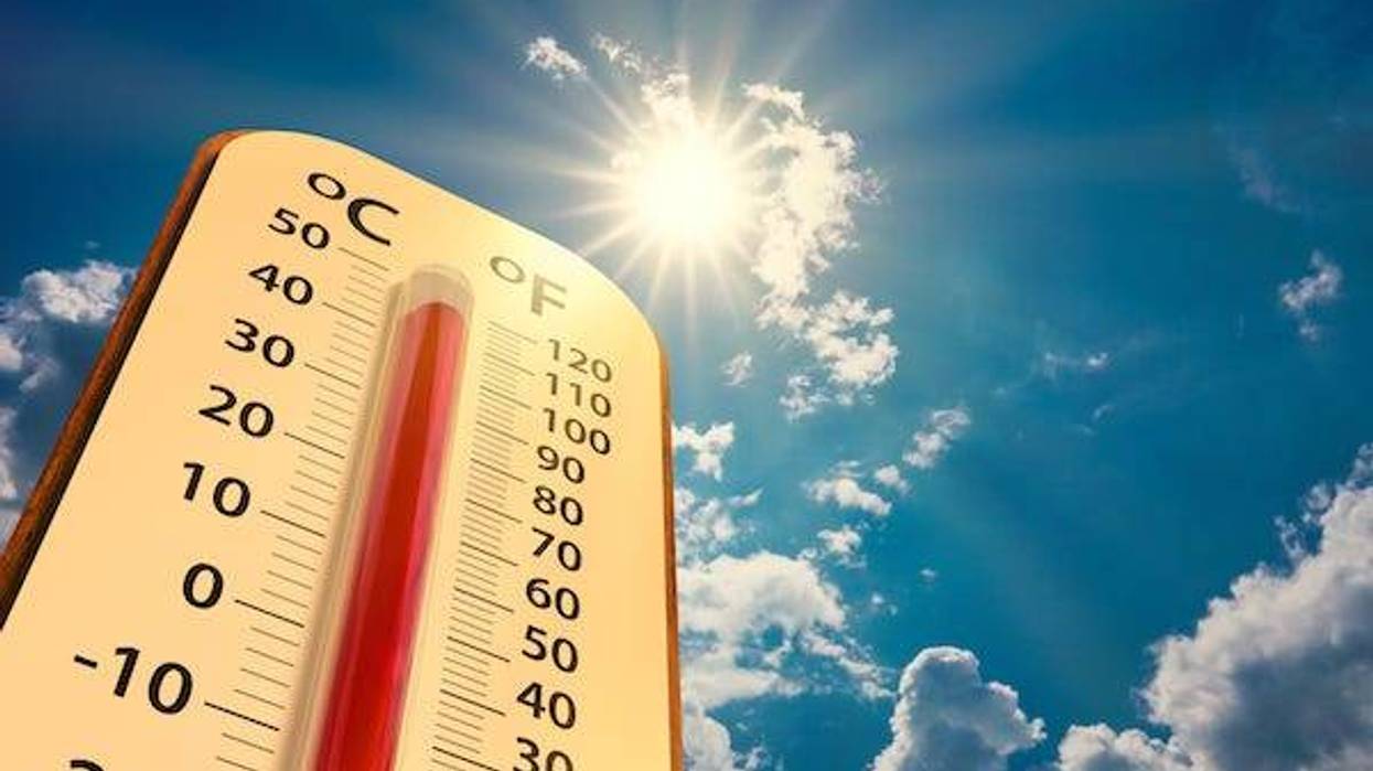 Thermometer showing high temperatures against blue, cloudy sky