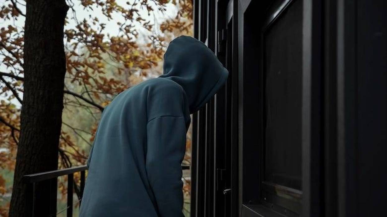 Thief in dark clothes picks door lock and enters house
