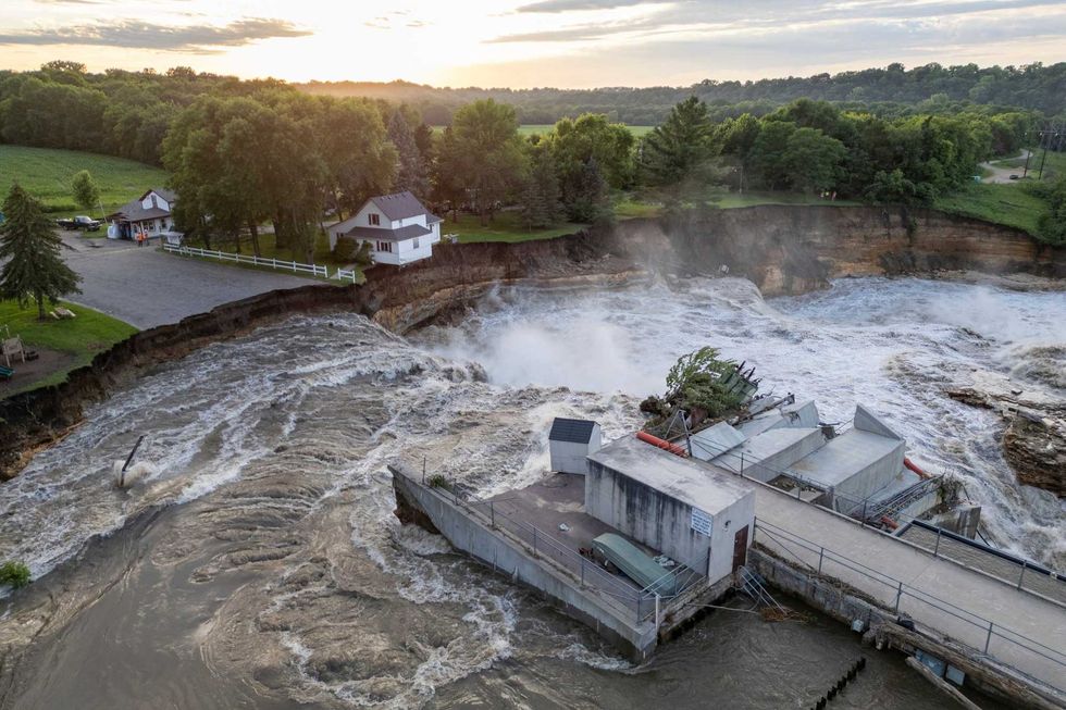This drone photo provided by AW Aerial shows a home as it teeters before partially collapsing into the Blue Earth River at the Rapidan Dam in Rapidan, Minn., Tuesday, June 25, 2024.