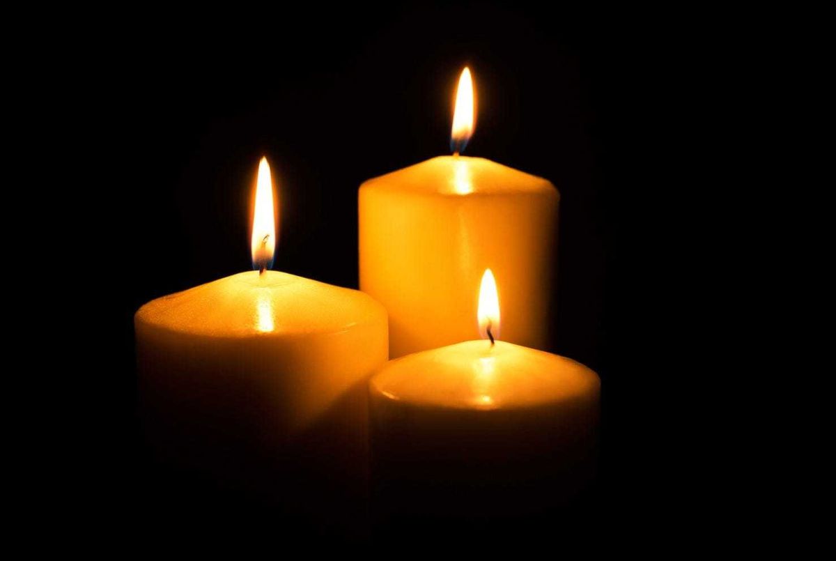 Three candles on a black background stock photo.