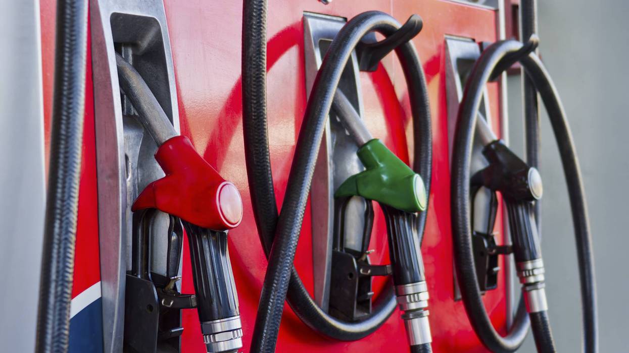 Three colored fuel nozzles (red, green, black) on a gas pump.