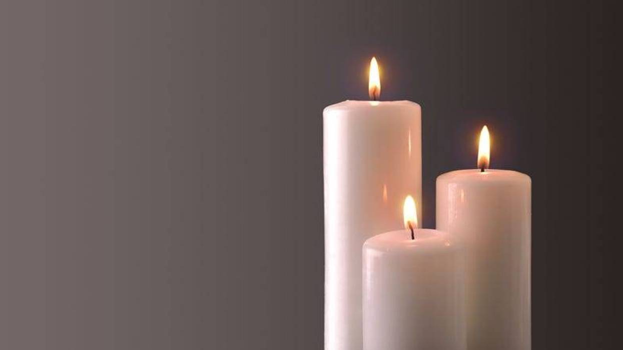Three lit candles of staggered heights, set against a plain background