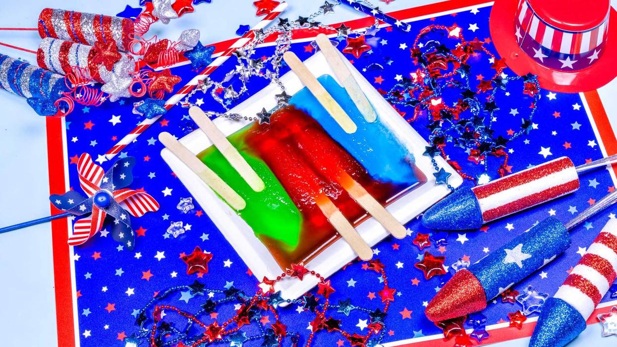 Three popsicles on a white plate melting against a colorful American patriotic backdrop celebrating July fourth and Memorial Day.