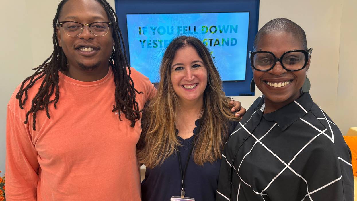 Three smiling people: a man with dreadlocks, a woman with long hair, and a woman with glasses.