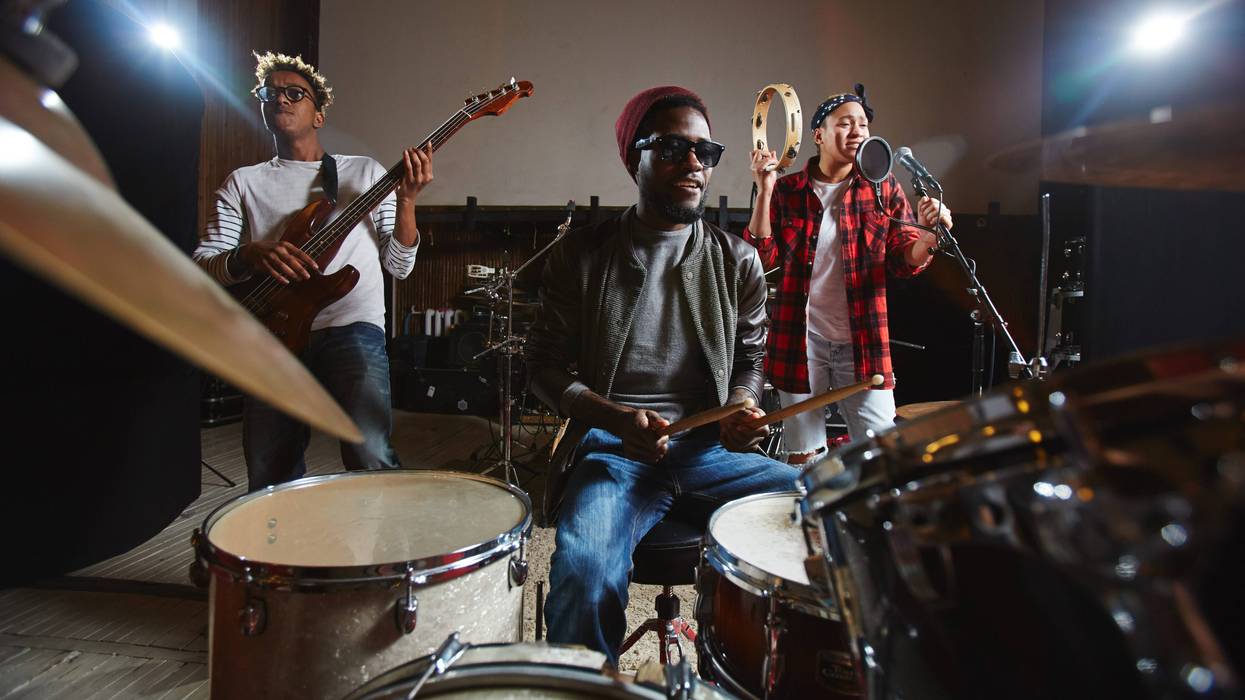 Three young musicians playing musical instruments and performing songs in studio of records