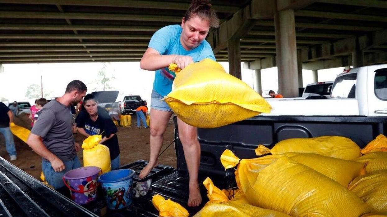 Tiffany Delee tosses a filled sandbag into the back of the family truck, while her husband Mike Delee, left, readies to tie up another bag, in Morgan City, La., Friday, July 12, 2019. The Delee's will use the bags to help protect their grandmother's house