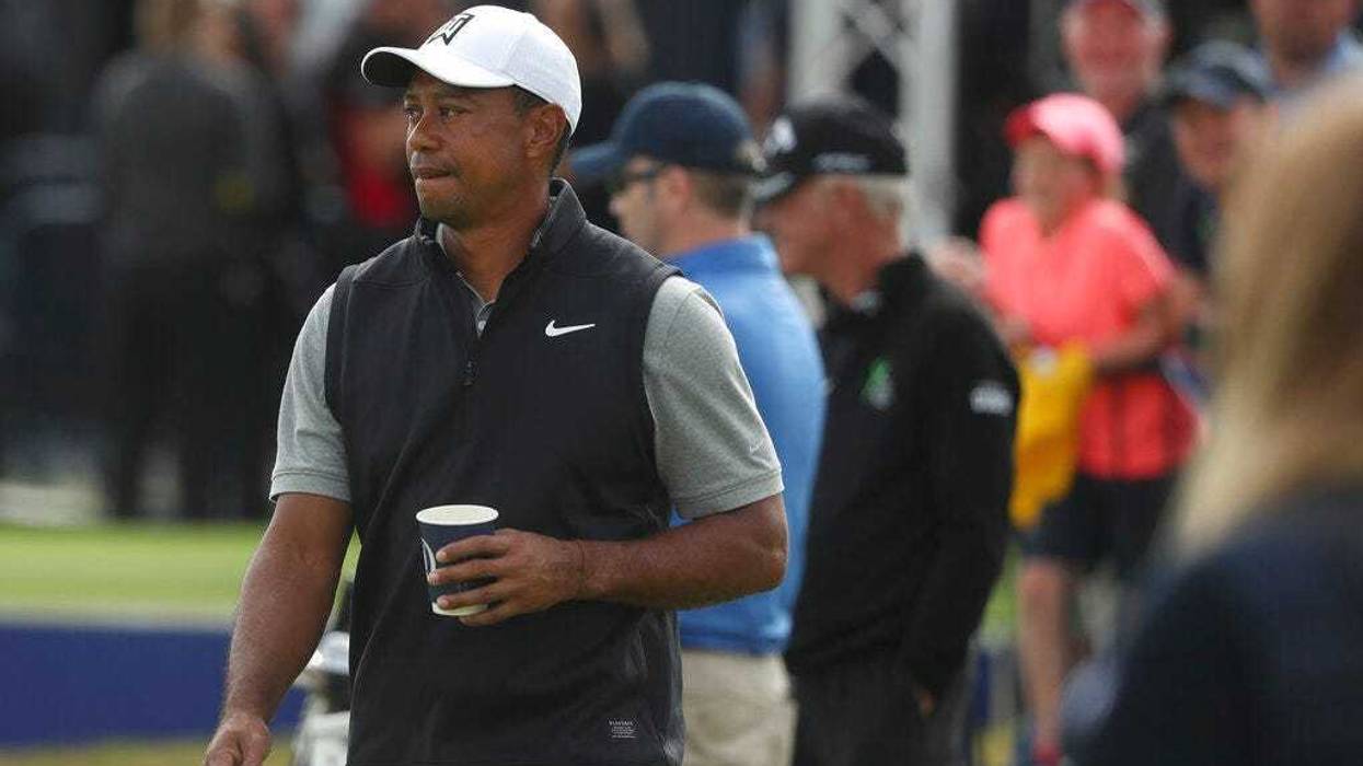 Tiger Woods of the United States holds a drink as he walks through the practice range ahead of the start of the British Open golf championships at Royal Portrush in Northern Ireland, Tuesday, July 16, 2019. The British Open starts Thursday.