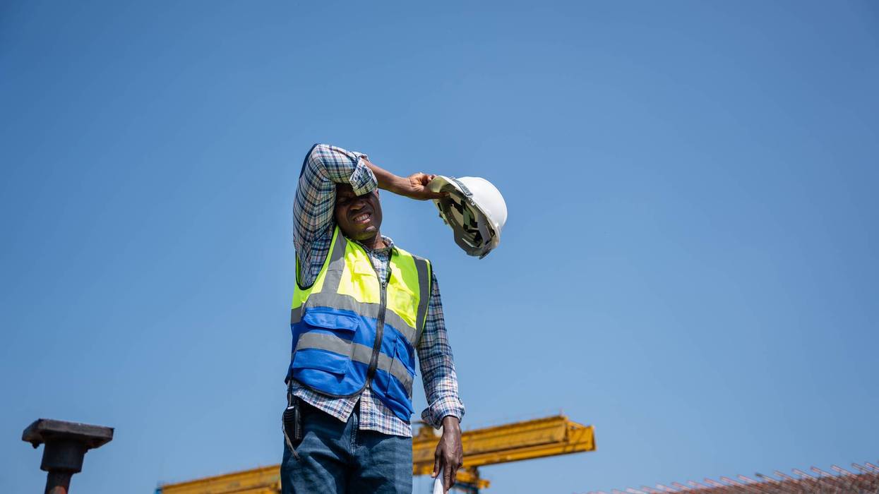 Tired Construction Worker Wiping Sweat Under the Hot Sun, Exhausted Engineer Taking a Break at Construction Site in Heat, Manual Labor in Extreme Weather, Worker Struggling with Heat Stress