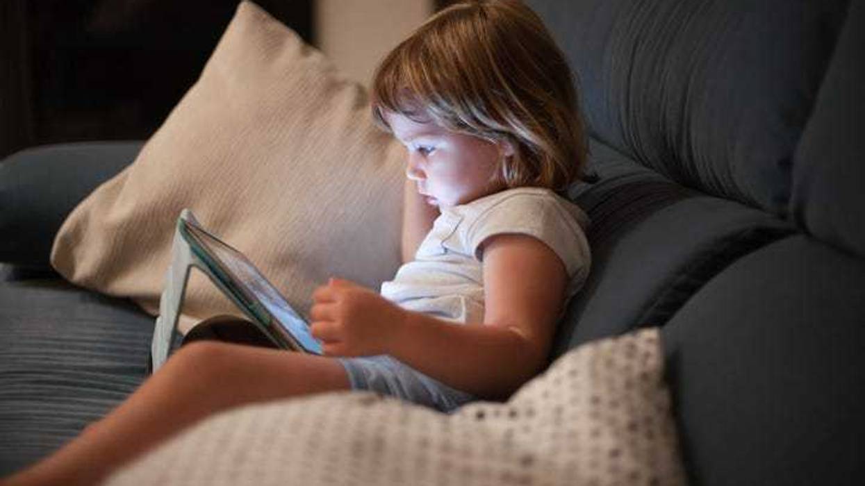 Toddler playing on a tablet on the couch.