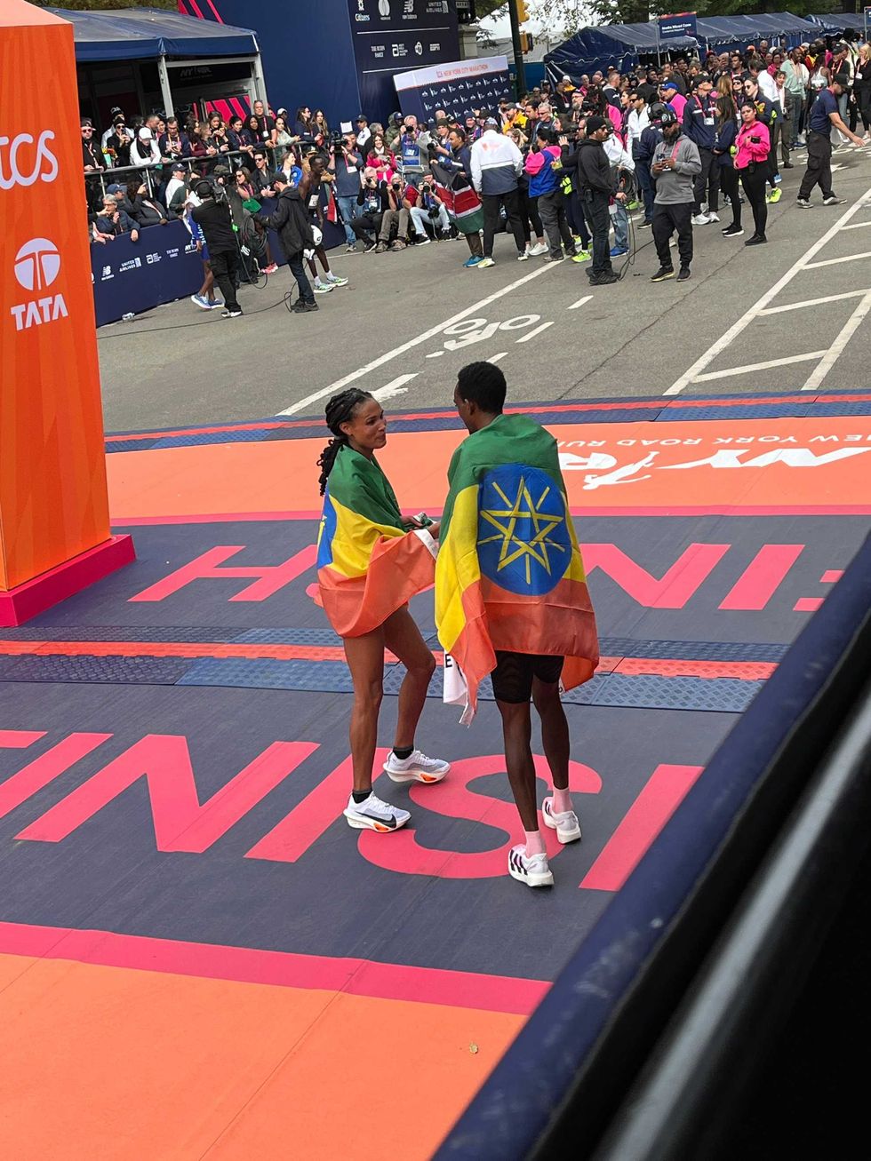 Tola and Gidey draped in Ethiopian flags following the race.