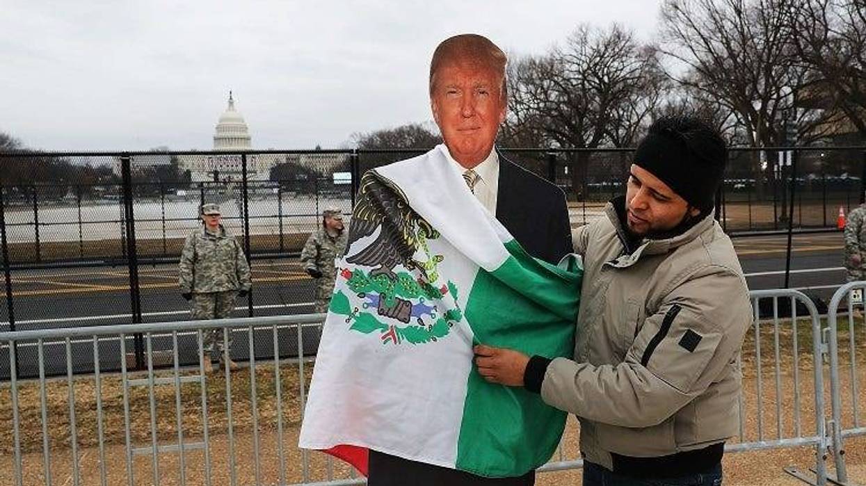 Tony Cervantes, a Zapatista activist who is against President Donald Trump, places a Mexican flag on a Trump cut-out on the National Mall following the inauguration of President Trump on January 20, 2017 in Washington, DC. Washington and the entire world