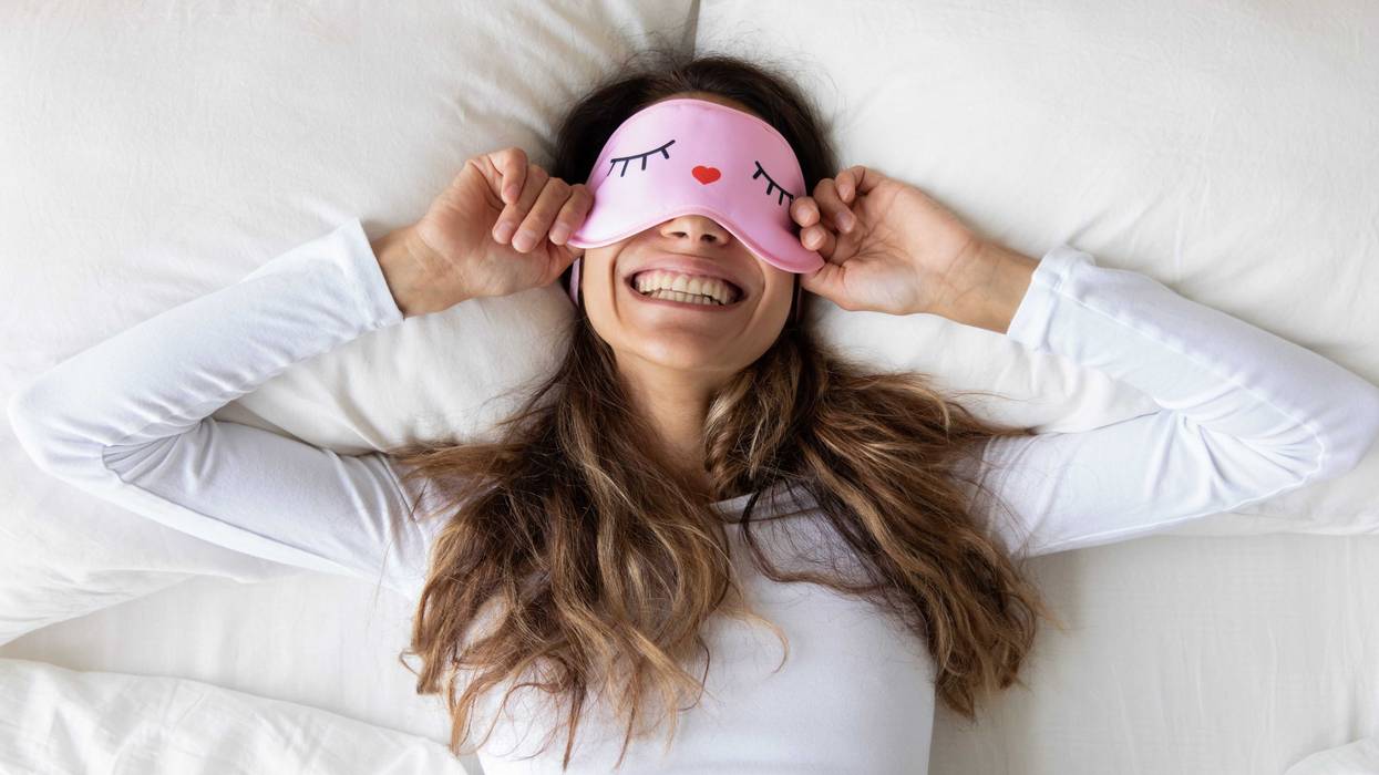 Top view close up happy woman wearing funny sleeping mask
