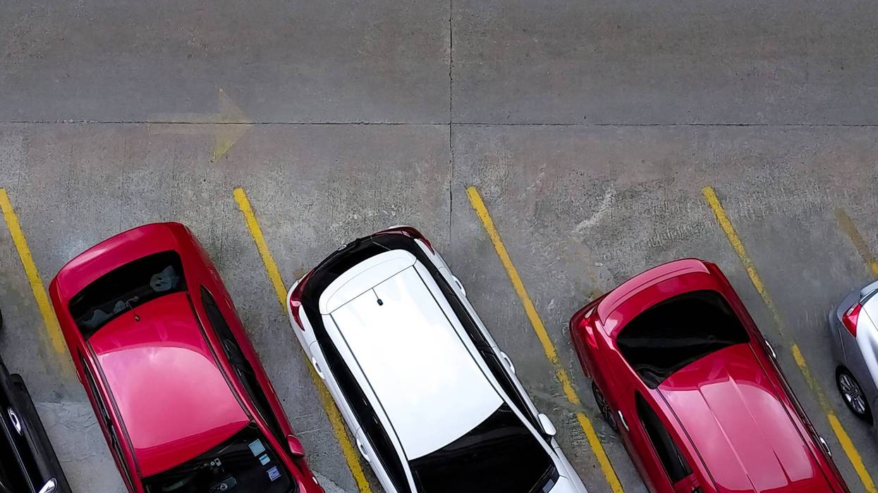 Top view of car parked at concrete car parking lot with yellow line of traffic sign on the street