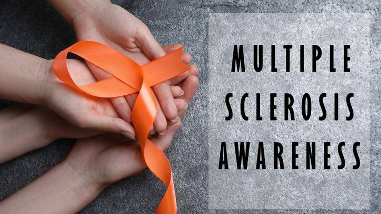 top view of hands holding an orange ribbon for Multiple Sclerosis Awareness