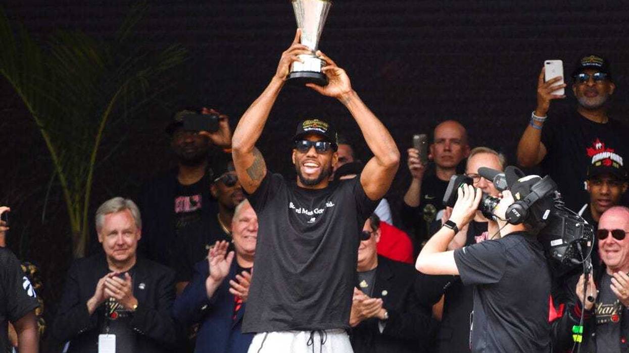 Toronto Raptors forward Kawhi Leonard hoists the MVP trophy next to teammates during the team's NBA basketball championship parade in Toronto, Monday, June 17, 2019.