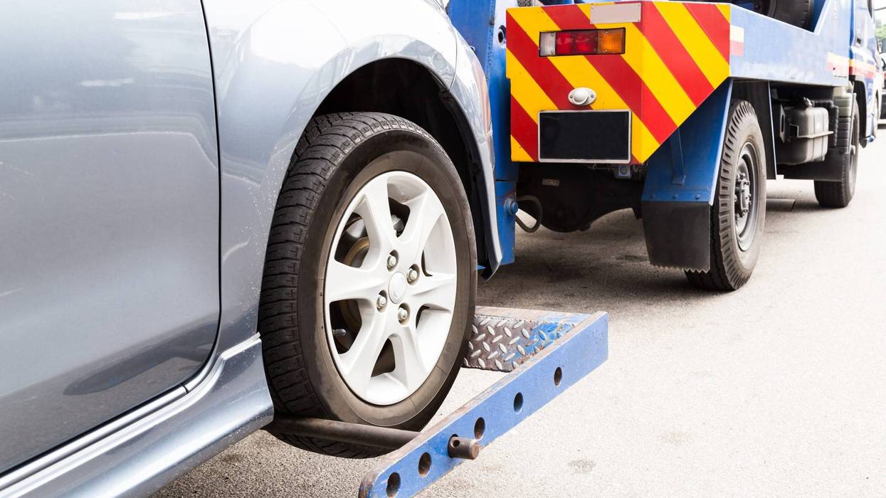 Tow truck towing a car on the street.