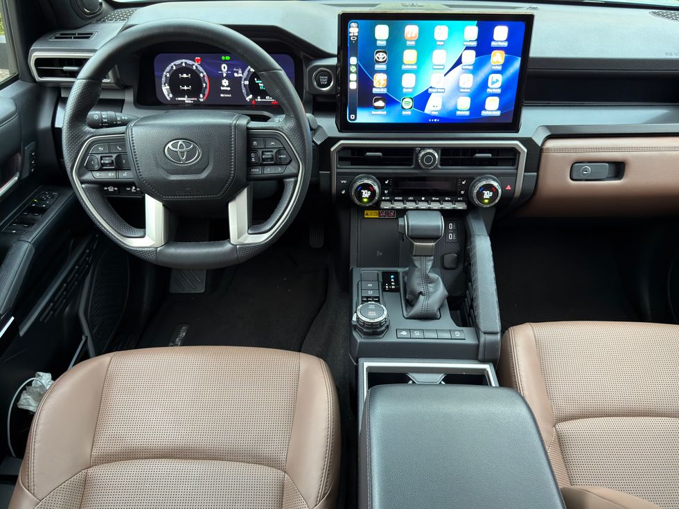 Toyota car interior: digital dash, large infotainment screen, brown leather seats.