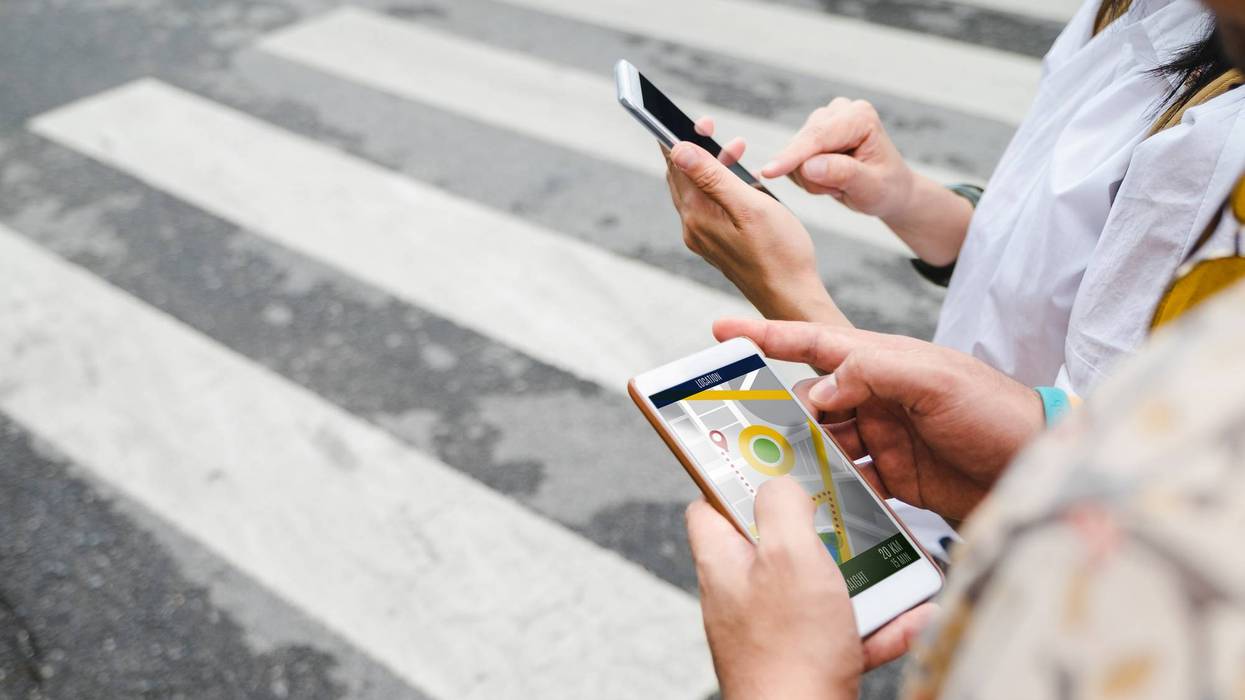 Traveler use map on mobile phone app to search for route location of place with gps on street when travel in city,Technology in lifestyle .
