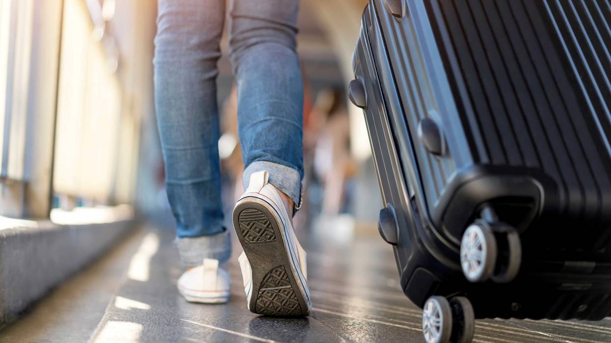 traveler wearing tennis shoes pulling suitcase