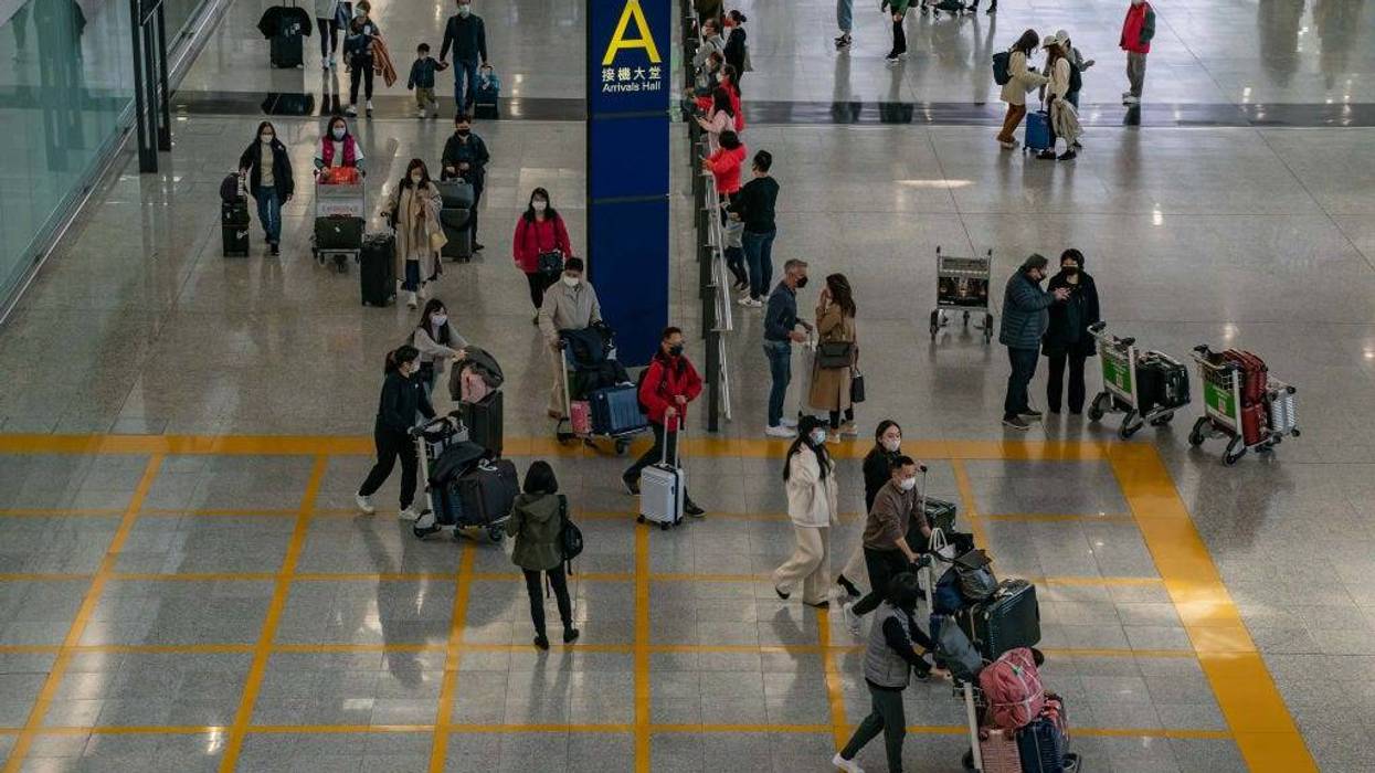 Travelers walk with their luggage at the arrival hall of the Hong Kong International Airport on December 30, 2022 in Hong Kong, China.