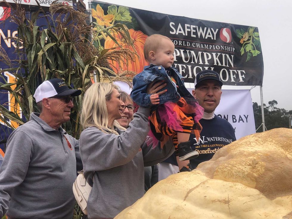 Travis Gienger and his family, including his daughter Lily, look at the record setting pumpkin while at the Safeway World Championship Pumpkin Weigh-Off in Half Moon Bay.