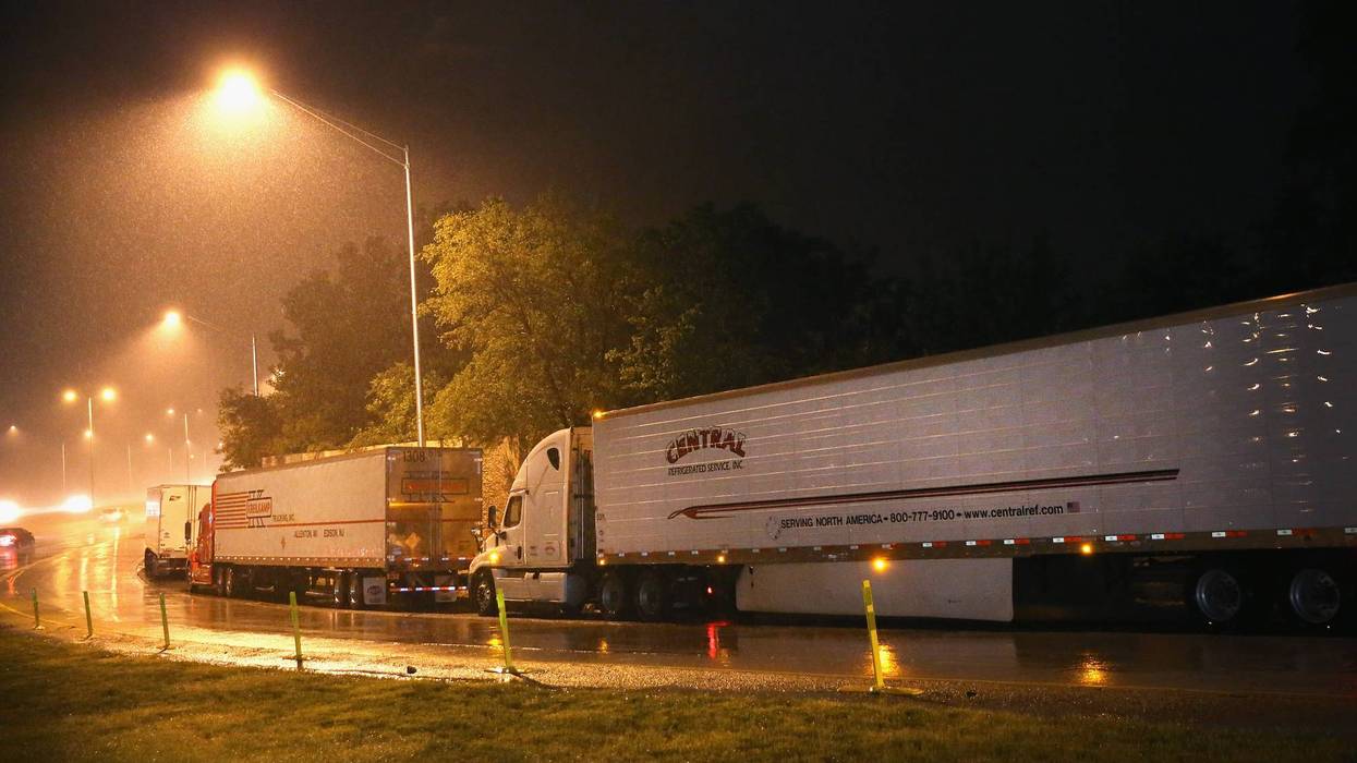 Truck drivers rest on a highway ramp on a rainy evening on the outskirts of Chicago on June 10, 2014