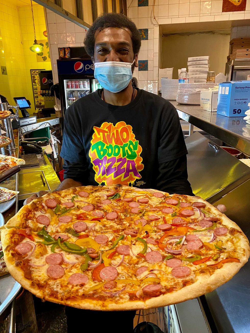 Two Boots employee Michael Perry shows off a fresh-out-of-the-oven "Mr. Ze" pizza at the chain