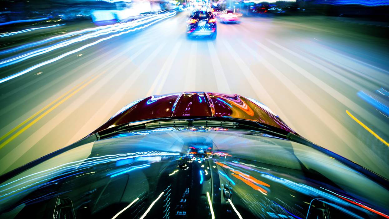 two cars speeding at night with blurred passing lights