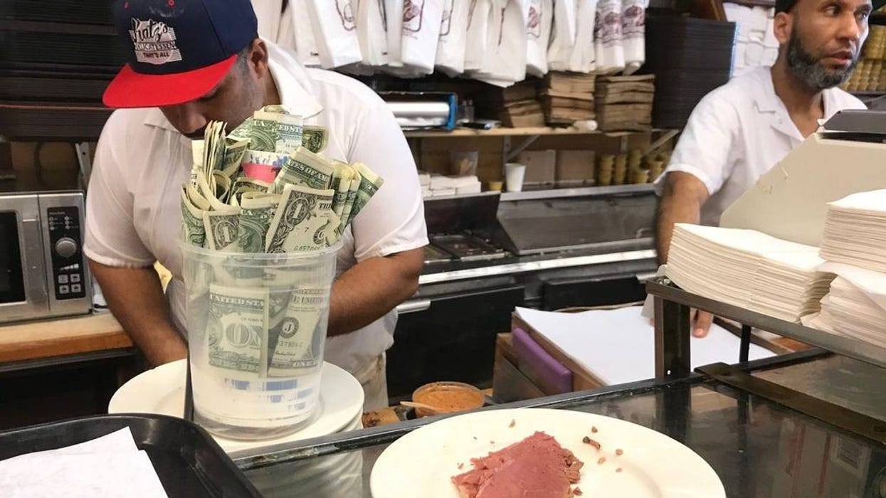 Two cooks work, with a tip jar sitting in front of them
