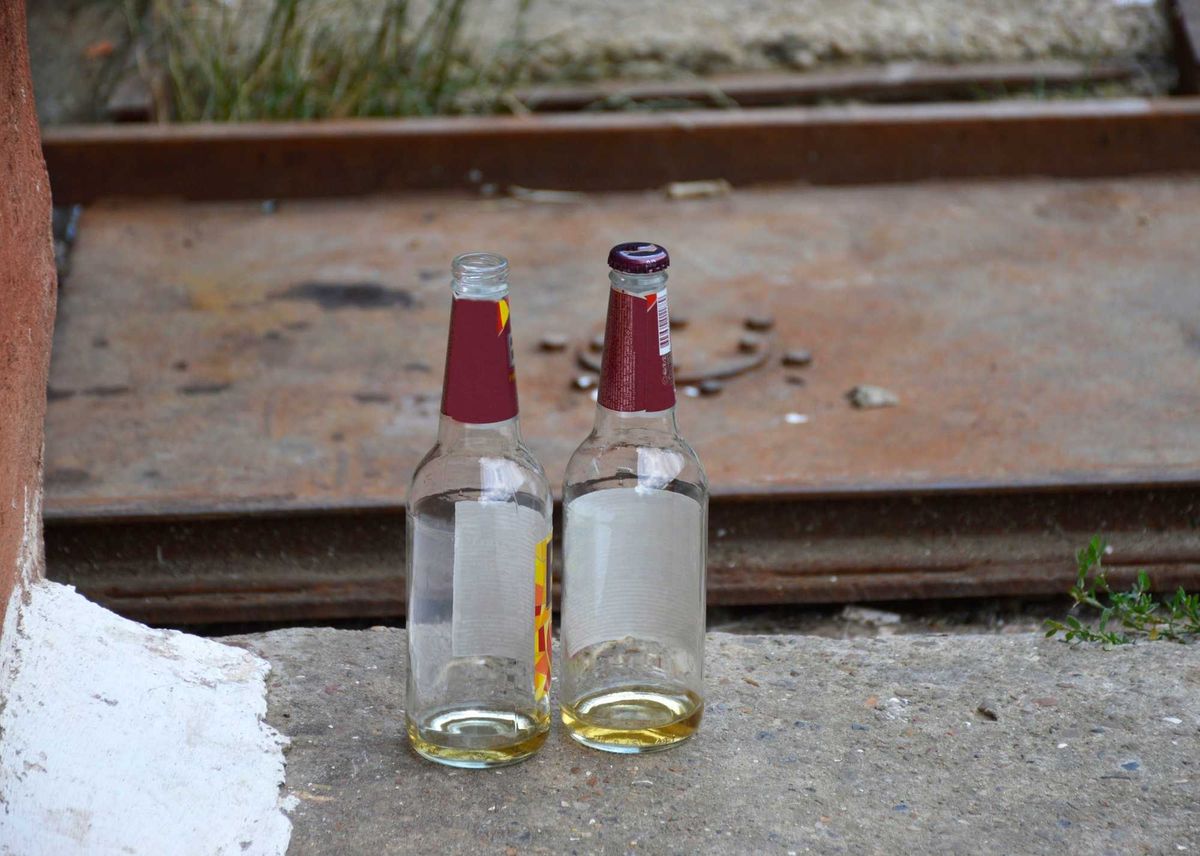 Two empty beer bottles on the side of the road.