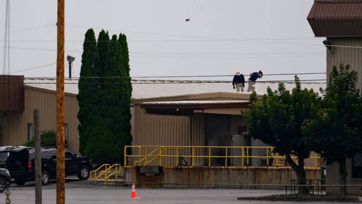 Two FBI investigators scan the roof of AGR International Inc, the building adjacent to the Butler Fairgrounds, from which alleged shooter Matthew Thomas Crooks fired at former President Donald J. Trump