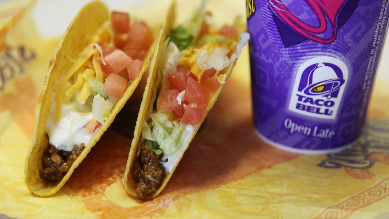 Two hard shell tacos leaning against a soda cup bearing the Taco Bell logo