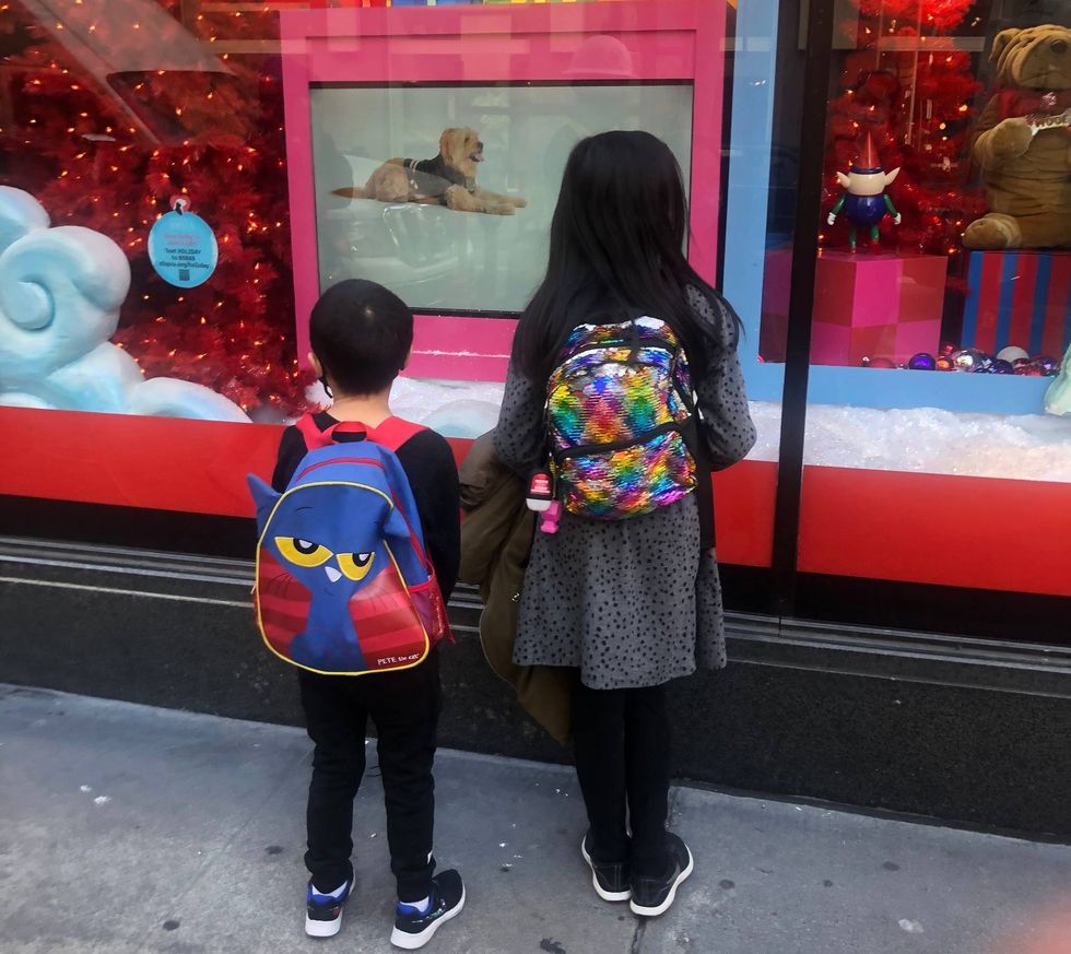 Two kids look into the now-virtual puppy window at Macy