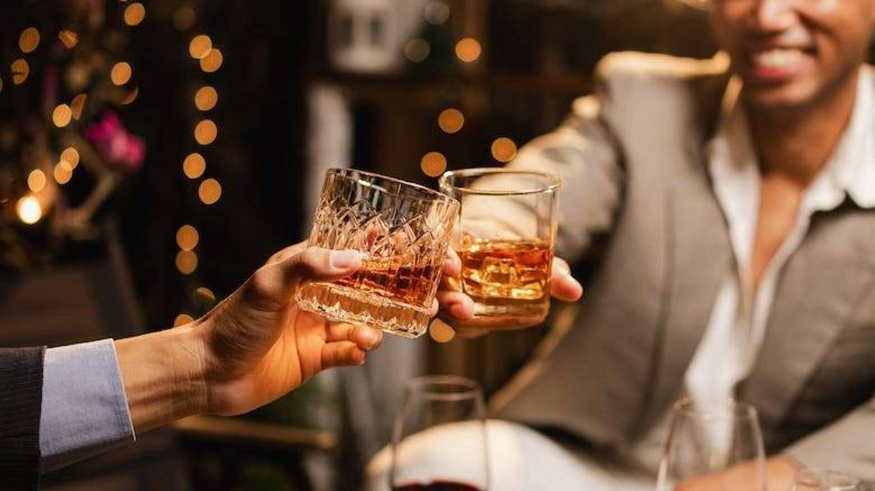 Two men clinking glasses of whiskey