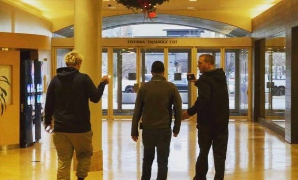 Two men holding phones in another man