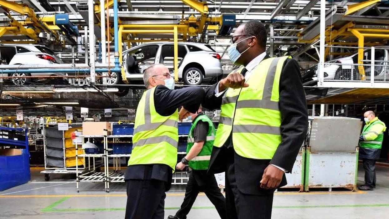 Two men in yellow vests bumping elbows in car plant