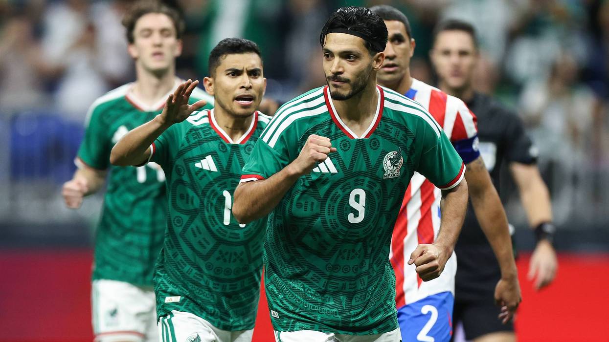 Two Mexican soccer players in green patterned jerseys reacting during a match, one clenching fist.