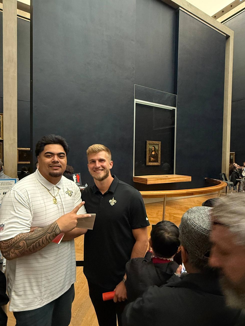 Two New Orleans Saints players smiling in front of the Mona Lisa at the Louvre.