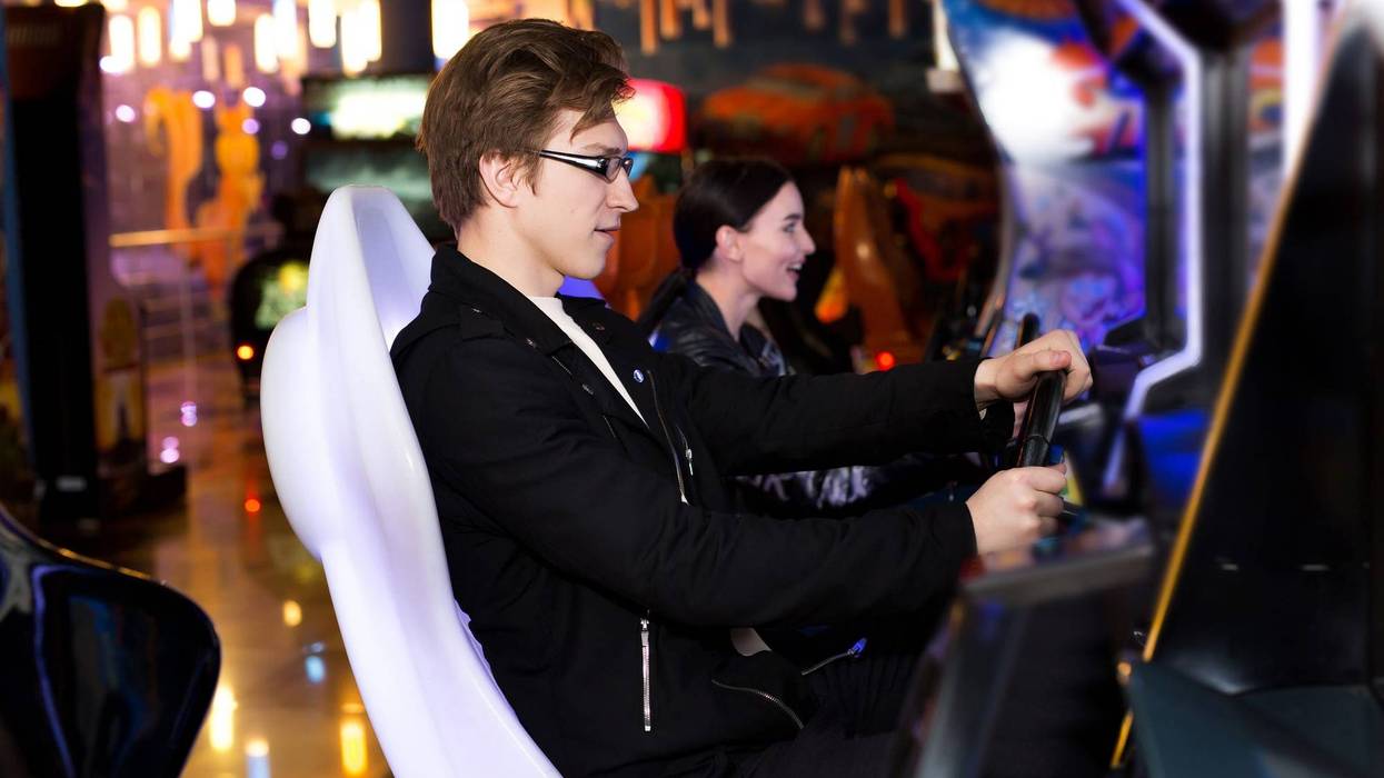 Two people in an arcade playing a racing car game