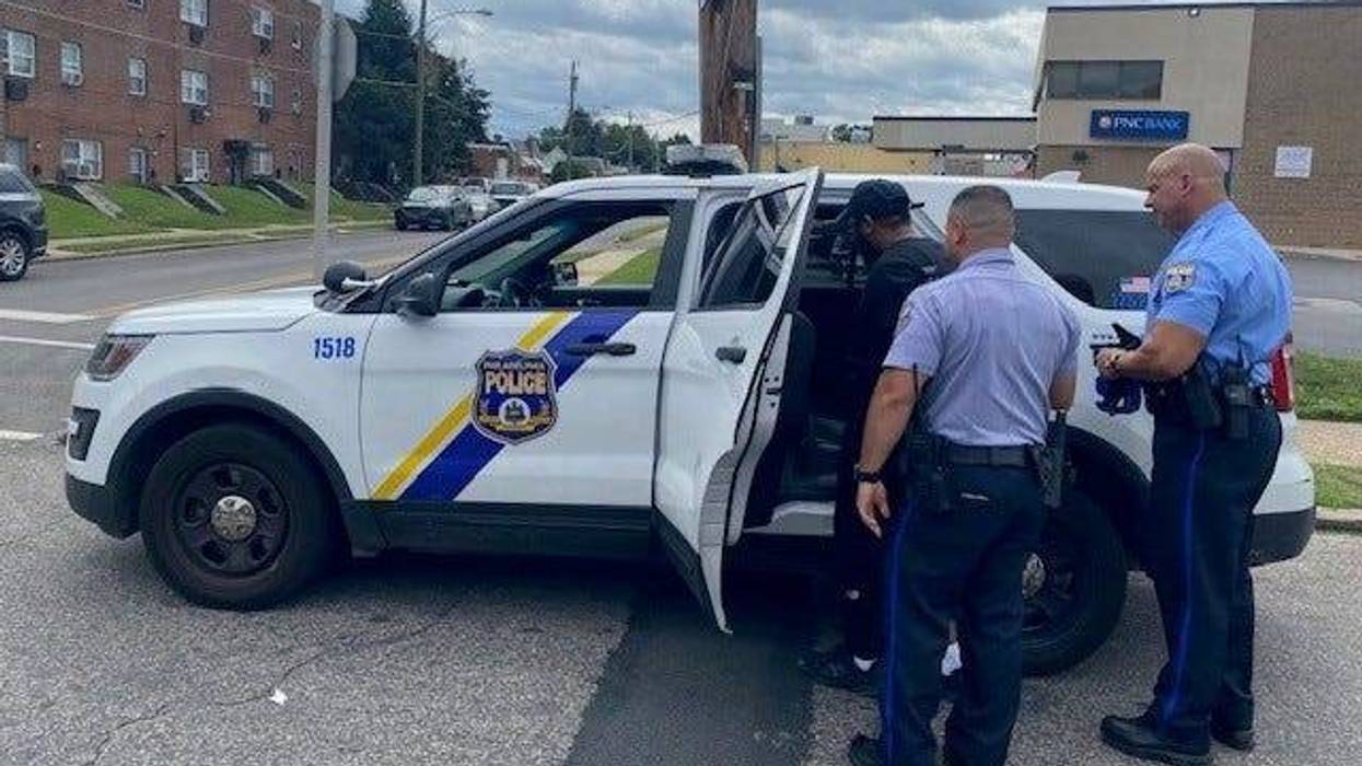 Two Philadelphia police officers place suspect Rasheem Trusty into a squad vehicle.