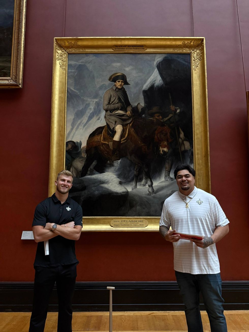 Two Saints players pose in front of Paul Delaroche's Napoleon Crossing the Alps painting.