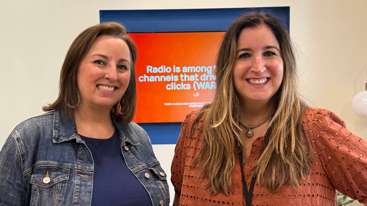 Two smiling women next to a screen about radio's role in driving clicks.