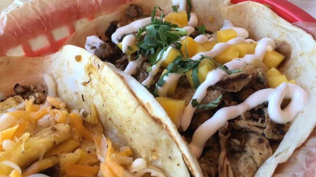 Two tacos: one with meat, mango, cilantro & crema; another with scrambled eggs & shredded cheese.