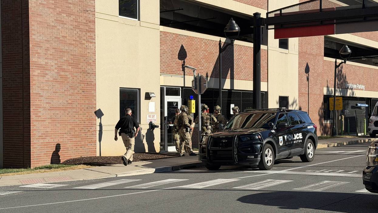 Two teams of Delaware state troopers in tactical gear enter a parking garage near Wilmington Hospital on Tuesday, June 16.