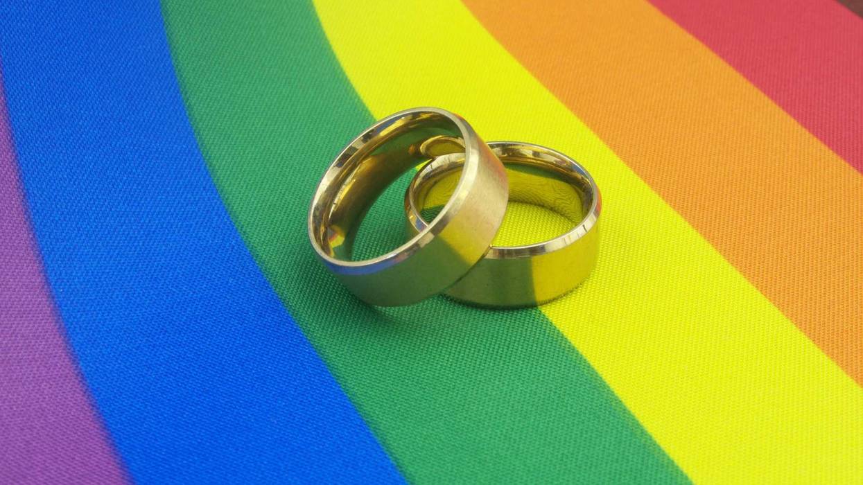 Two wedding bands on a rainbow flag.