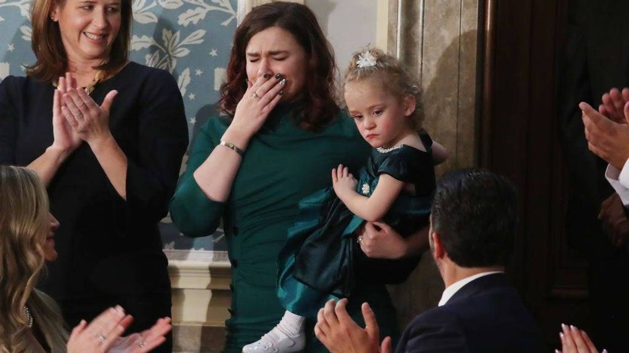 Two-year-old Ellie Schneider is held by her mother, Robin, at the State of the Union Address in the US House Chamber.