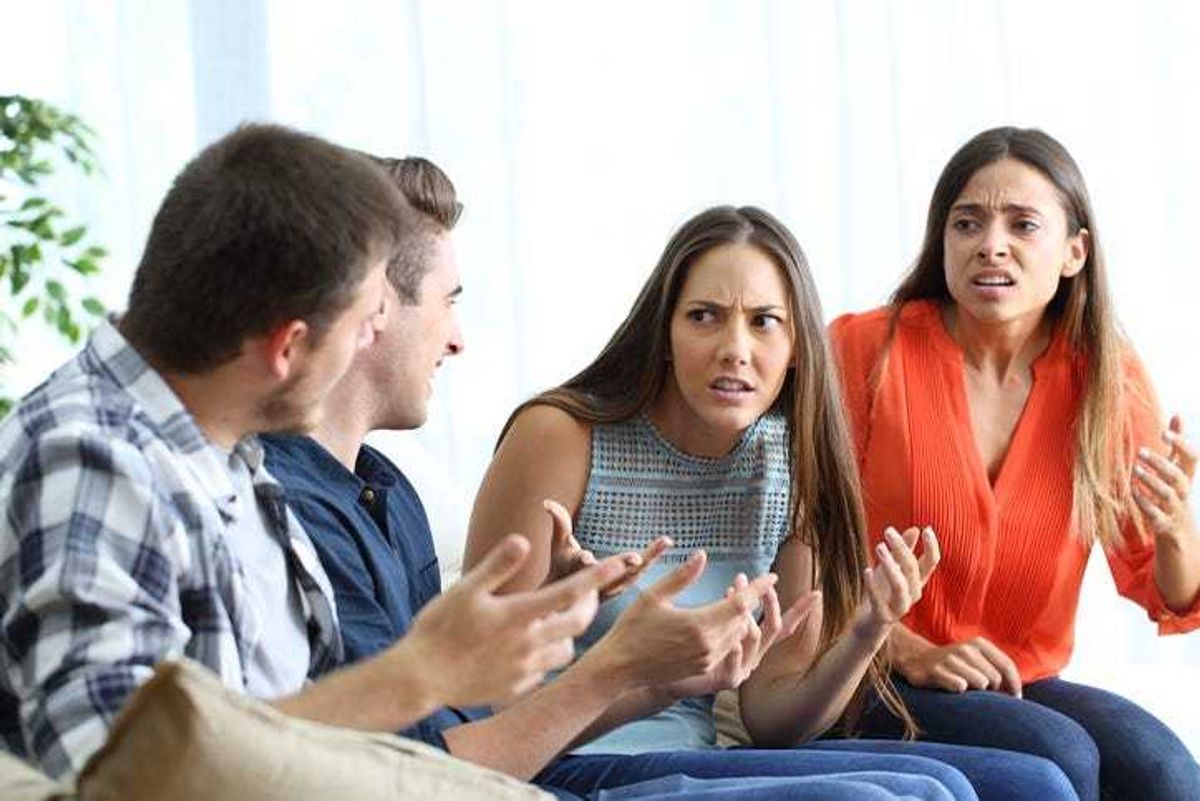 Two young men and two young women sitting on a couch arguing